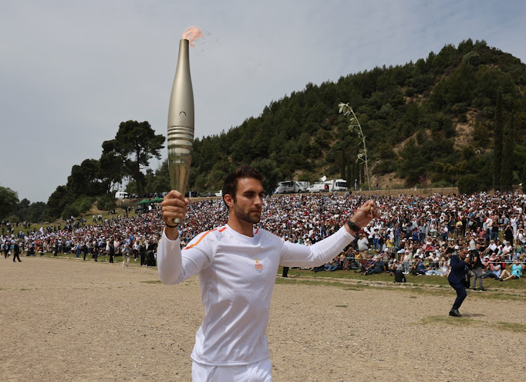 The first torchbearer, Greek rower Stefanos Ntouskos, carries the flame during the start of the relay after the flame-lighting ceremony for the Paris 2024 Olympics at Ancient Olympia in Greece on Tuesday.