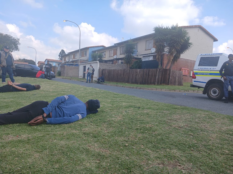 The two suspects seen lying on the ground in Booysens, Johannesburg, are suspected be members of a syndicate that has been linked to violent crimes in Gauteng, including more than 30 murders.