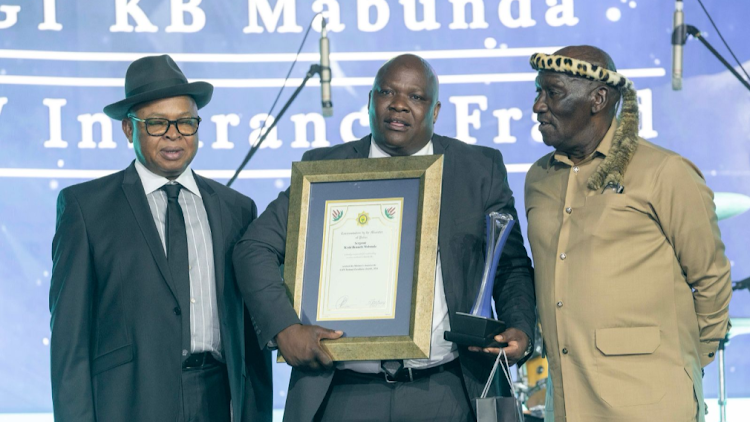 Sgt Keshi Benneth Mabunda receives the police minister's special award from Bheki Cele and deputy police minister Cassel Mathale.