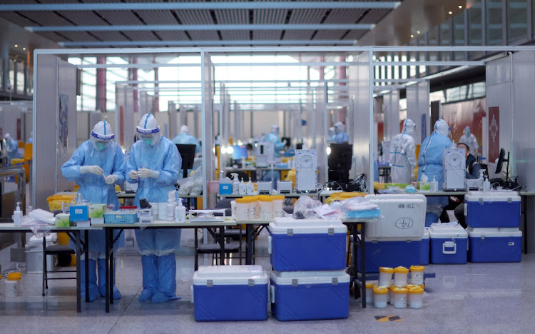 Staff members wearing personal protective equipment (PPE) designed to prevent the spread of the coronavirus disease (Covid-19), work at a Covid-19 testing site at Beijing Capital International Airport ahead of the Beijing 2022 Winter Olympics in Beijing, China, January 31, 2022.