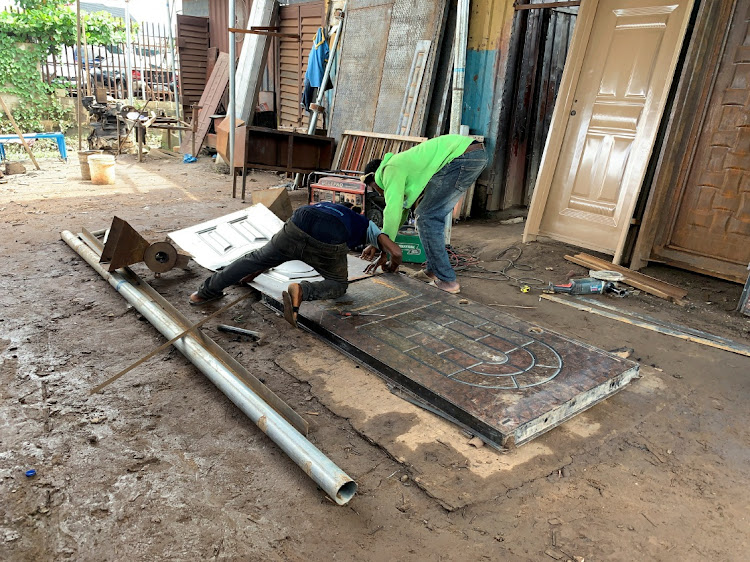 Shola Ojo, a Nigerian welder, works with his co-worker on a metal door in his workshop in Lagos, Nigeria, June 3, 2023.