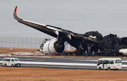 Officials investigate a burnt Japan Airlines Airbus A350 plane after a collision with a Japan Coast Guard aircraft at Haneda International Airport in Tokyo, Japan, on January 3 2024.