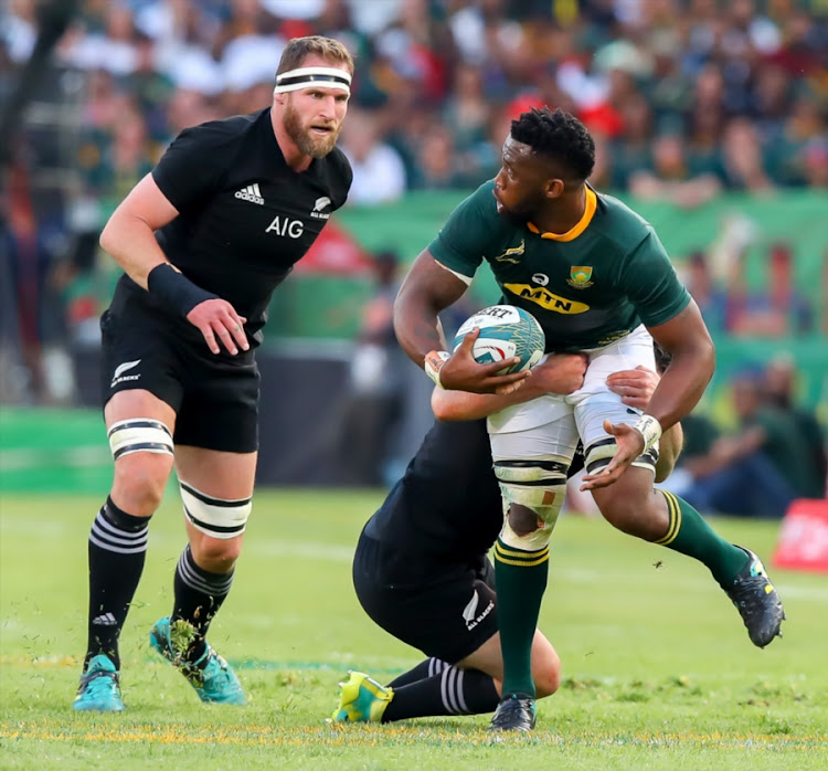 Springboks captain Siya Kolisi (R) pulls away from a tackle as his New Zealand counterpart charges in during the Rugby Championship match between South Africa and the All Blacks at Loftus Versfeld in Pretoria on October 06, 2018.