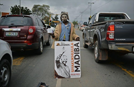 A street child holds up a poster bearing the image of South African former president Nelson Mandela as he begs during rush hour in Mthata near Nelson Mandela's former home Qunu.