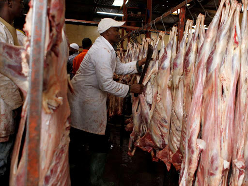 A butcher arranges goat meat inside a slaughterhouse.