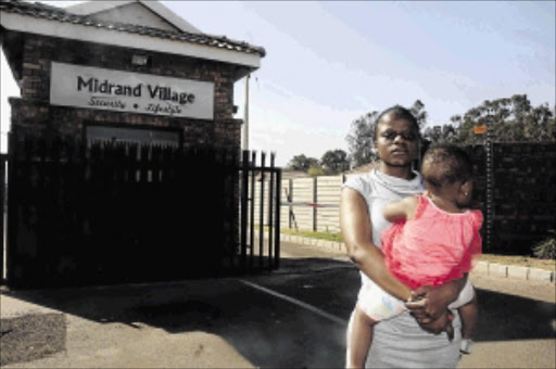 shaken : Child minder Sharon Mannzwa holds the baby she was locked in a house with after the child's medical doctor father was late in paying the rent Photo: Thulani Mbele