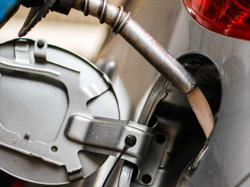 An attendant fills up a car at a petrol station.