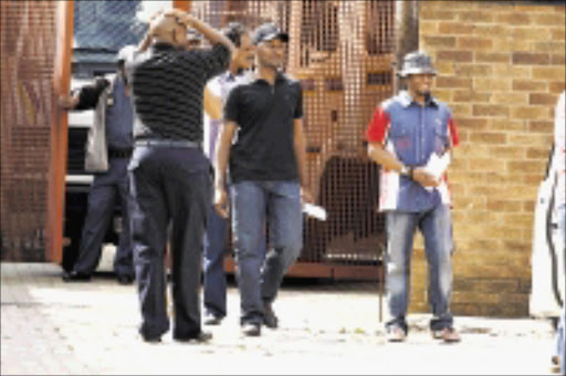 IN THE LIMELIGHT: Suspected crime kingpin William Mbatha, right, arrives in shackles at the Germiston magistrate's court yesterday. Pic: MOHAU MOFOKENG. 21/10/2009. © Sowetan.
