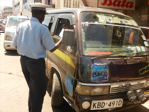 A traffic police inspecting a vehicle at a road block. /FILE