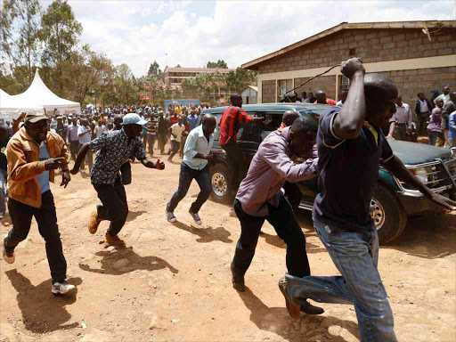 The Vehicle carrying Kibra MP Ken Okoth speed off as others take to their heels from the Raila Educational Centre after rowdy youth pelted him with stones on October 26, 2016. Photo/Jack Owuor