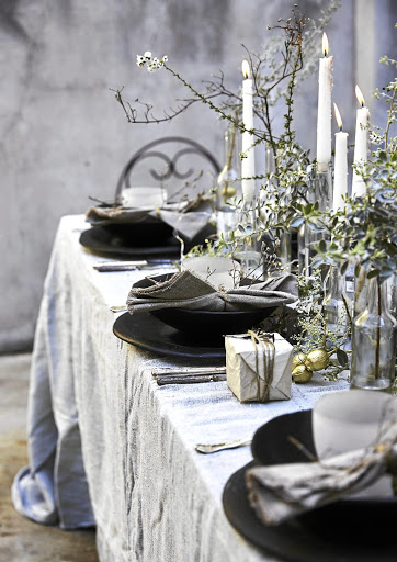 Glass bottles of varying sizes hold taper candles and sprigs of fynbos.