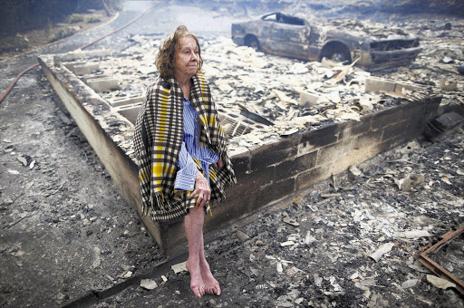 STUFF OF NIGHTMARES: Fran Collings, 82, sits stunned in the remains of her Tokai home, destroyed by fire yesterday. Rescue personnel continued to fight the blaze for a fourth night last night