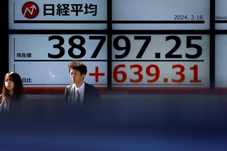 Passersby walk past a screen displaying Japan’s Nikkei share average outside a brokerage in Tokyo, Japan, on February 16 2024. Picture: REUTERS/ISSEI KATO