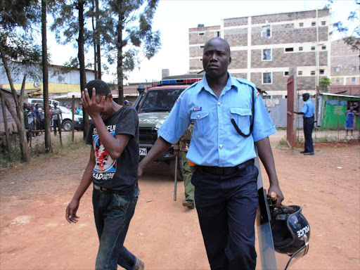 NABBED: A police officer arrests a young man in Kariobangi North during the fracas yesterday