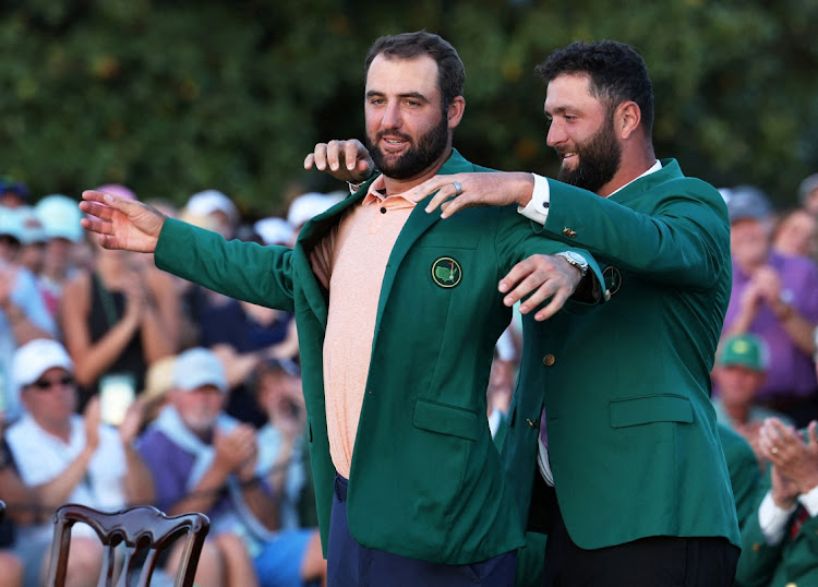 Scottie Scheffler of the US is presented with the green jacket by Spain's Jon Rahm after winning The Masters at Augusta National Golf Club on April 14, 2024