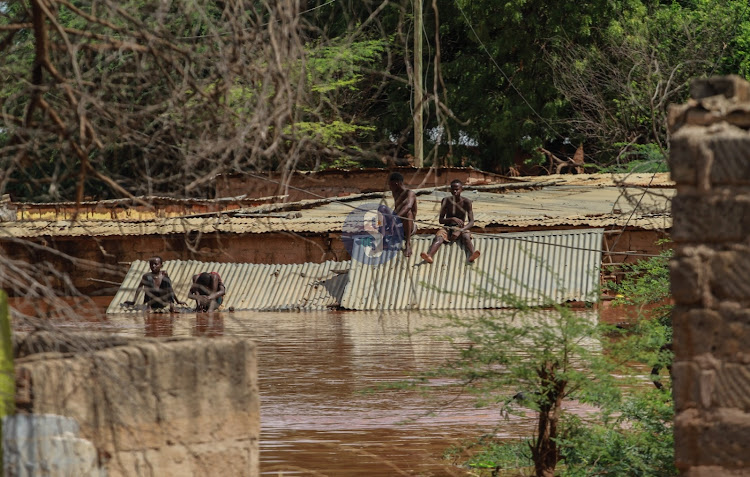 Residents sit on the roofs of their submerged homes in Mororo after River Tana burst its banks on April 27, 2024.