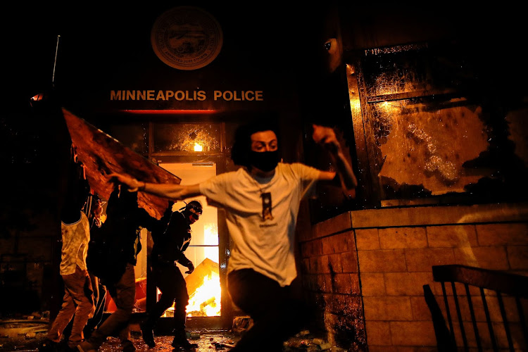 Protesters react as they set fire to the entrance of a police station as demonstrations continue after a white police officer was caught on a bystander's video pressing his knee into the neck of African-American man George Floyd, who later died at a hospital, in Minneapolis, Minnesota, U.S., May 28, 2020.