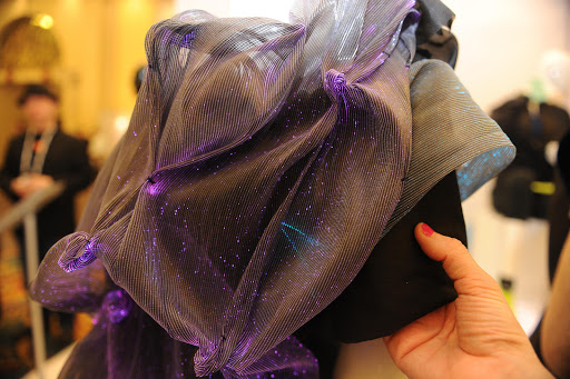 Designer Amy Winters presses a sensor in the sleeve of her colour-changing dress to change the dress from purple to the blue colour represented in the sleeve at the 2014 International CES, January 9, in Las Vegas, Nevada. The dress is made of "LuminousTex" fabric with fibre optics woven in and sensors in the sleeves. Light travels through the cloth, which changes colors when the wearer presses a slender sensor inside the left sleeve. © /