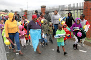 Some of the children  who braved the cold and rainy weather walk alongside their parents and guardians after receiving their  toys from the Motsepe Foundation at Orlando Stadium in Soweto yesterday. 