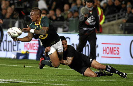 Springbok flyhalf Elton Jantjies tries to get rid of the ball despite All Black scrumhalf Aaron Smith's close attention.
