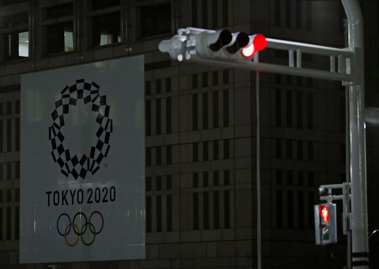 A banner for the upcoming Tokyo 2020 Olympics is seen behind traffic lights in Tokyo, Japan, on March 23 2020.