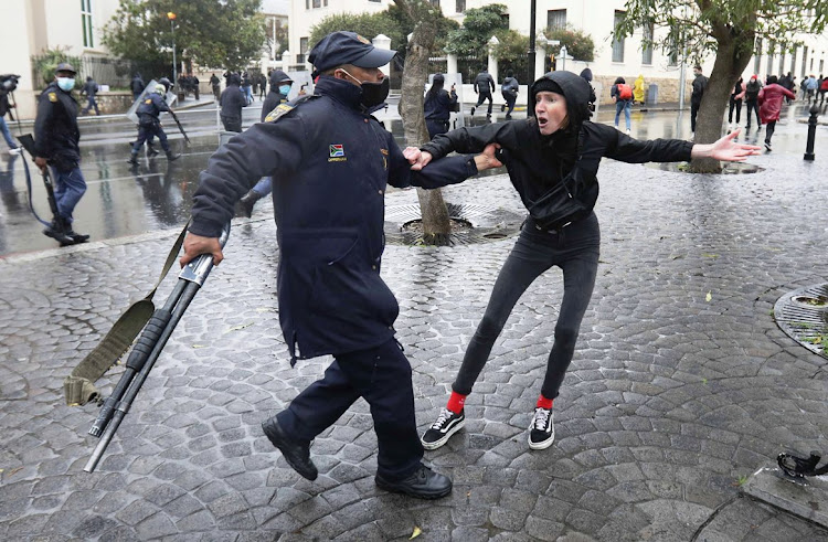 A police officer grabs a protester against gender-based violence outside parliament on August 29 2020.