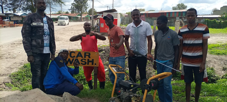 Athi River MCA Jeremiah Kaloi's personal assistant Victor Masila (2ndR) presents a car washing pump to a youth group at Athi River in Mavoko, Machakos County on April 14, 2024.