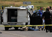 A suspect, under heavy police guard, lies on the road after a foiled cash-in-transit heist. File photo.