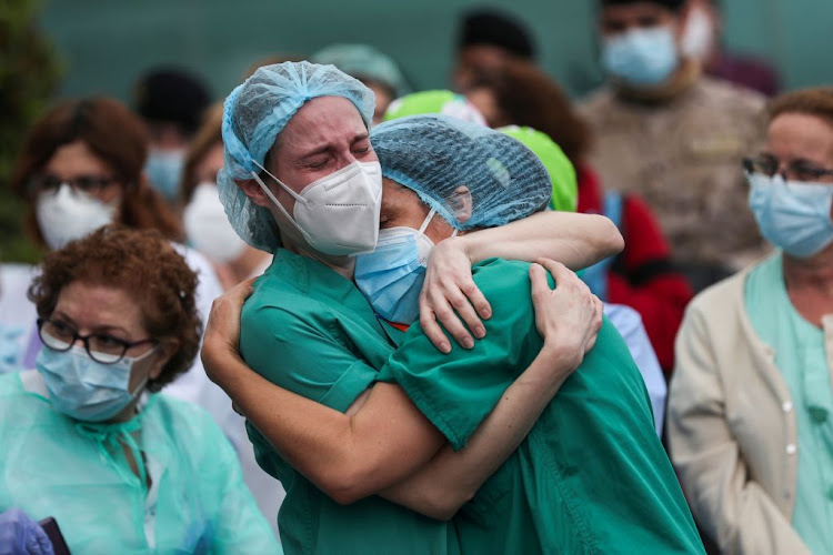 Health workers wearing protective face masks react during a tribute for their co-worker Esteban, a male nurse that died during the Covid-19 outbreak, outside the Severo Ochoa Hospital in Leganes, Spain, on April 13 2020.