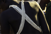 The white cross-body beadwork that identifies the wearer as a returned initiate. When they leave, they wear only the loincloth, a different stick and a grass ball on their foreheads.