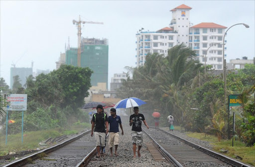 Sri Lankan pedestrians carry an umbrella during a downpour of heavy rain off Mount Lavinia beach on the outskirts of Colombo on June 8, 2013.