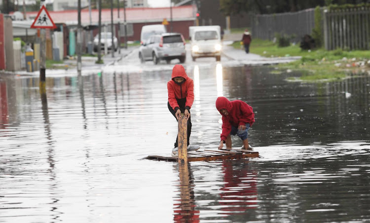 Kids from Hanover Park on the Caper Flats plays on a pallette on a waterlogged road outside their home. Heavy rains and strong winds cause flooding, waterlogged roads on the Cape Falts and informal settlements in the Western Cape
