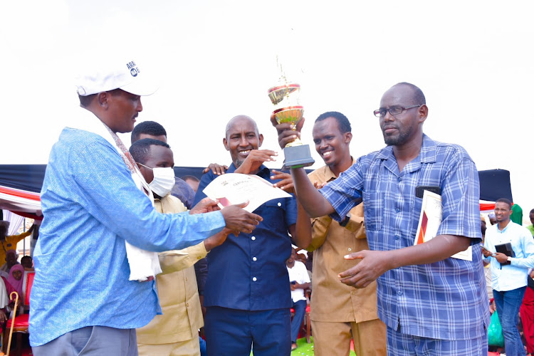 Lagdera MP Abdikadir Hussein[L] hands over a trophy to a teacher during the ceremony.