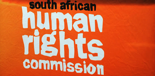South Afrian Human Rights Commission CEO Kayum Ahmed is silhouetted against a poster at a briefing on Wednesday, 31 October 2012 in Johannesburg on findings of the investigation into the killing of Free State activist Andries Tatane. The SAHRC investigated Tatane's death, during a protest in Ficksburg in April 2011, followed a complaint by the Council for the Advancement of the SA Constitution. It found that the police were not suitably equipped to quell public disorder during the protest and had failed to devise a plan to regulate and monitor the protest. The police used excessive force on Tatane resulting in his injuries and subsequent death. The findings had been forwarded to the police. Picture: Werner Beukes/SAPA