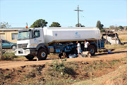 People fill water containers from an Aqua water tanker outside a Wartburg depot. Residents in the area haven’t had tap water for two weeks.