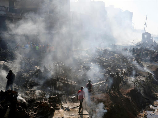 Rescue workers walk at the smouldering scene of fire that gutted down the timber dealership of the Gikomba market and nearby homes in central Nairobi, Kenya June 28, 2018. REUTERS