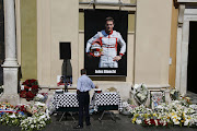 A man pays his respects below a poster showing late French Formula One driver Jules Bianchi, after the funeral ceremony for Bianchi at the Cathedrale Sainte Reparate in Nice on July 21, 2015, southeastern France. Nine months after his horror crash during the Japan Grand Prix in Suzuka, Bianchi died on July 17, 2015 in a hospital of his hometown of Nice from head injuries sustained in the October 5 accident. AFP PHOTO / VALERY HACHE