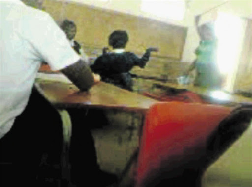 CAPTURED: Two frightened pupils are seen being on the receiving end of a beating by a teacher in this screen grab from a video taken by another pupil in the classroom at a school in Leandra, Mpumalanga