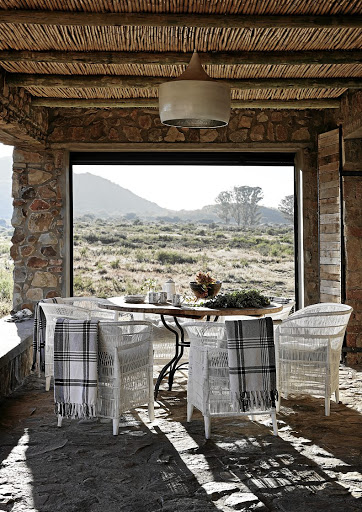 The stoep includes a dining nook protected by a glass wall that welcomes in views of Pink Hill. The ceiling is made from reeds found on the farm.
