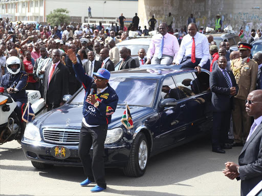 Nairobi senator Mike Sonko addresses supporters as President Uhuru Kenyatta look on along outer-ring road upon his arrival from the Hague Oct 09 2014.Photo/HEZRON NJOROGE