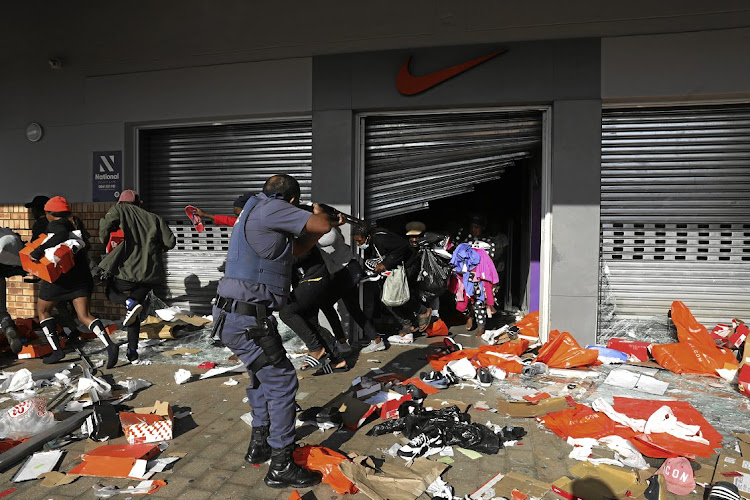 Looters flee from a police officer at a shop in the Springfield Value Centre in Durban. File photo.