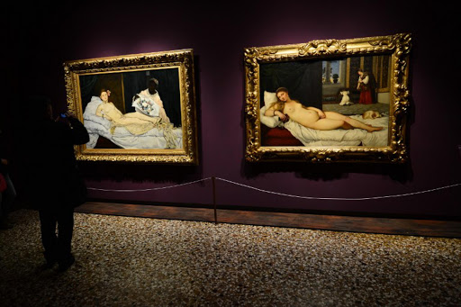 A man looks at Edouard Manet's 'Olympia' (L) and Titian's 'Venus of Urbino' on April 23,2013 in Venice, as he visit the exhibition "Manet Return to Venice", which runs until August 18, 2013, at the Doge'S Palace in Venice.