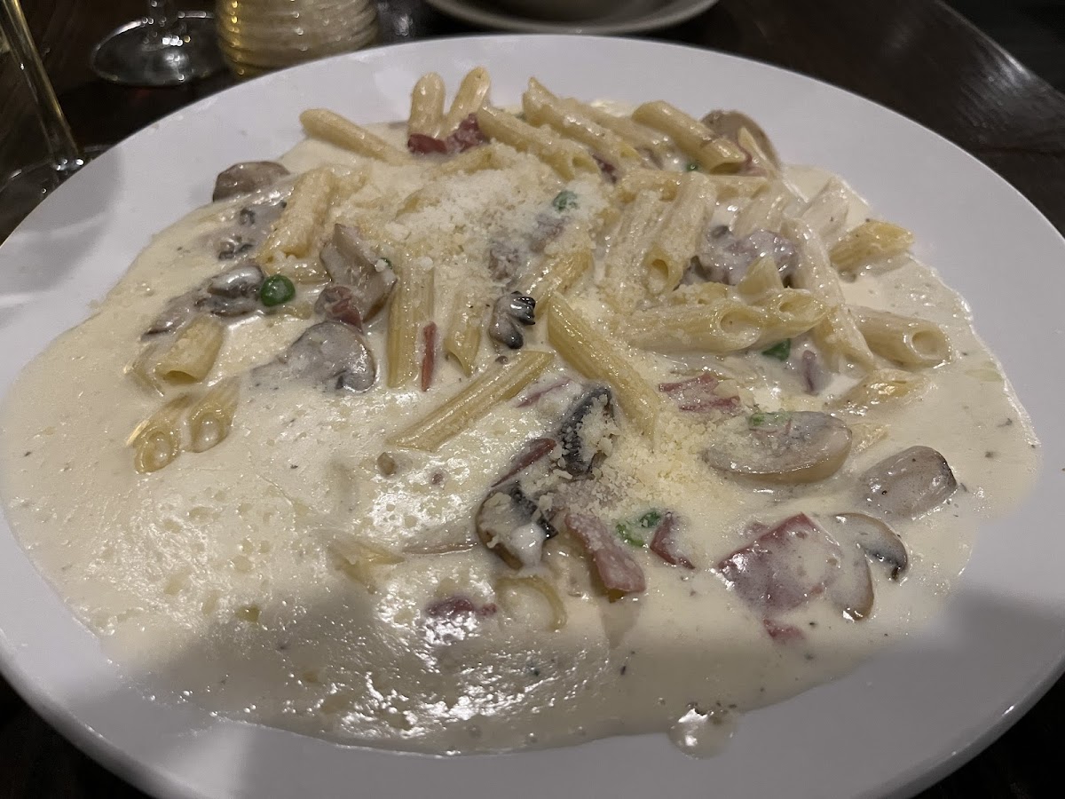 A custom order of GF penne, alfredo, prosciutto, mushrooms and peas.