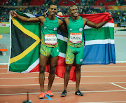 Henricho Bruintjies and Akani Simbine of South Africa hold up the national flag after finishing first and second in the men's 100m final during the evening session of the athletics at the Carrara Stadium on day 5 of the Gold Coast 2018 Commonwealth Games.