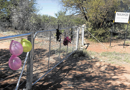 FARM GATE: The main gate to the Steenkamps' farm, bearing floral tributes to the slain couple and their daughter