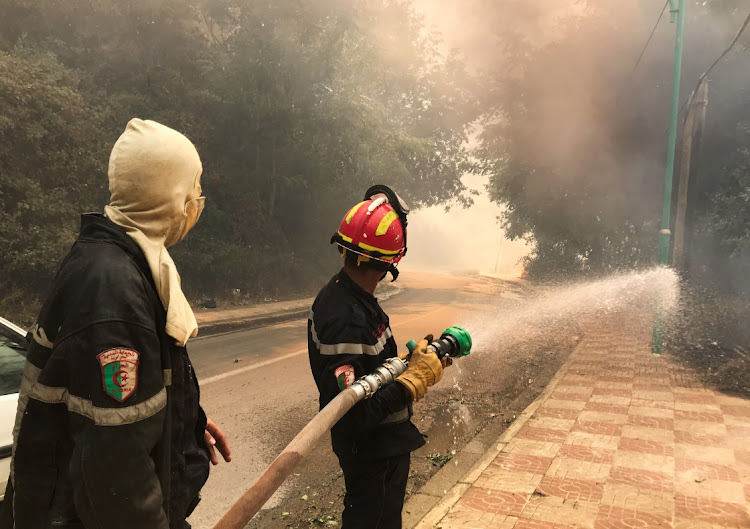 A firefighter uses a water hose during a forest fire in Ain al-Hammam village in the Tizi Ouzou region, east of Algiers, Algeria on August 10, 2021.
