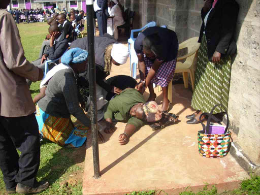 A parent of Kiganjo Mixed Day Secondary School is given first aid after she fainted during the meeting on Monday / NDICHU WAINAINA