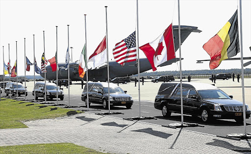 HALF-MAST: A convoy of hearses with the remains of victims of the Malaysia Airlines disaster leaves Eindhoven airport for a military base in Hilversum yesterday. The Dutch king and queen and families of the deceased were at the airport when the coffins arrived from Ukraine