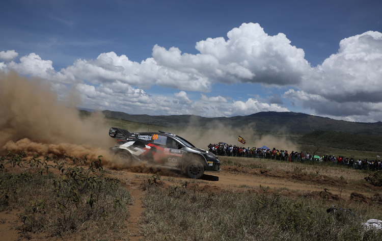 Fans watch as a rally car leaves behind a cloud of dust at the WRC Safari Rally shakedown in Naivasha on March 27, 2024.