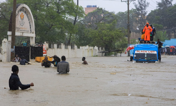 Passengers wade through flood water after getting evacuated from a public transport bus following heavy rains in Kisauni district of Mombasa, Kenya, on November 17 2023.